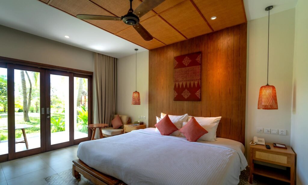 Elegantly designed hotel room featuring a king-sized bed, ceiling fan, and outdoor view.