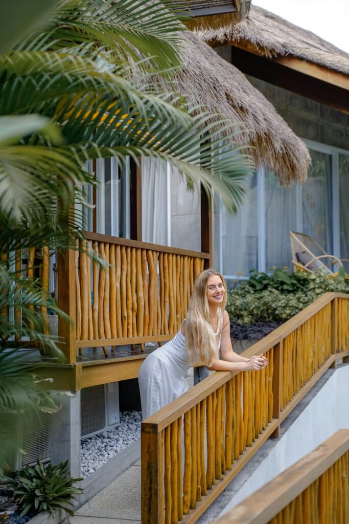 Woman enjoying a peaceful moment on a tropical resort balcony surrounded by lush greenery.